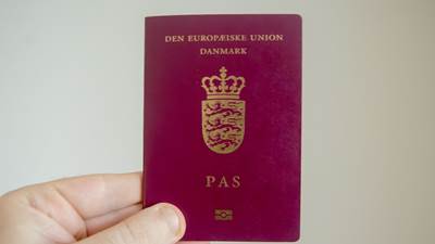 En hånd holder et dansk pas