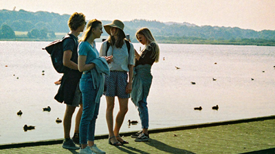 Fire unge mennesker står ved en sø