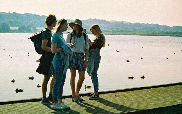 Fire unge mennesker står ved en sø
