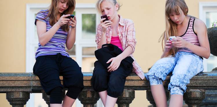 Tre unge piger med mobiltelefoner