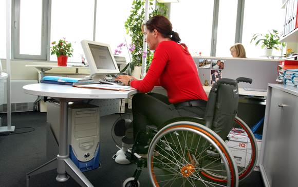 Kvinde med handicap sidder i kørestol ved skrivebord