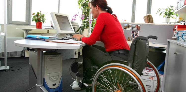 Kvinde med handicap sidder i kørestol ved skrivebord