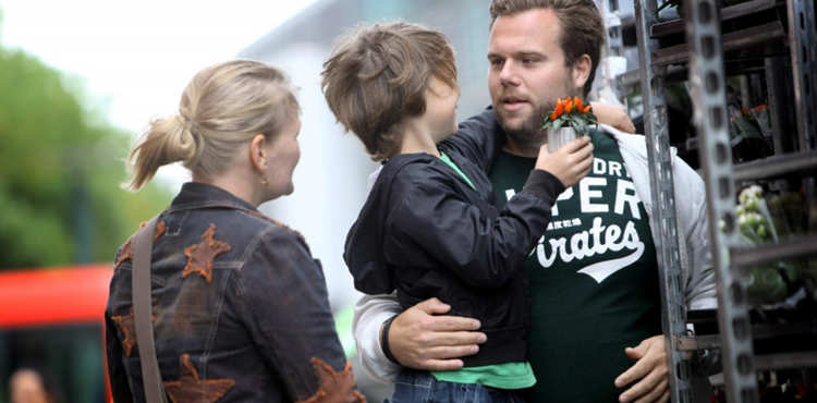 Familie med mindre barn står ved udendørs blomsterhandel