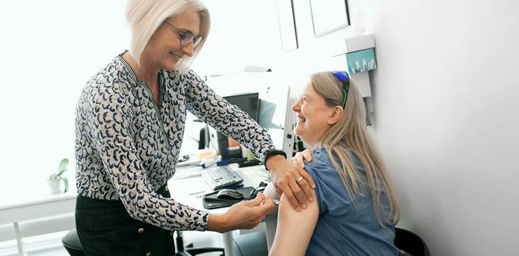 Læge giver injektion i overarmen på kvinde