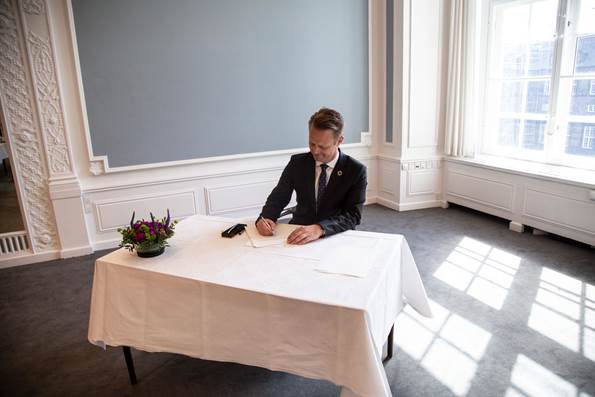 Udenrigsminister Jeppe Kofod underskriver løfteerklæring om at overholde grundloven. Han sidder ved et bord med en hvid dug 