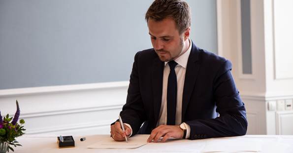 Erhvervsminister Simon Kollerup underskriver løfteerklæring om at overholde grundloven