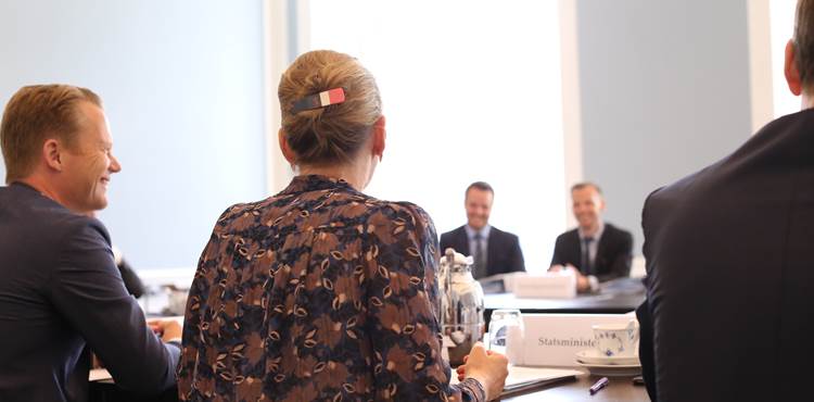 Statsminister Mette Frederiksen set bagfra med knold i håret og med spænde ved mødebord til første ministermøde i regeringen