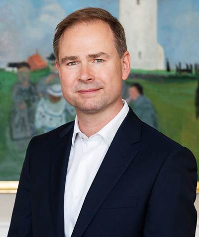 Finansminister Nicolai Wammen med sort blazer og hvid skjorte foran maleri