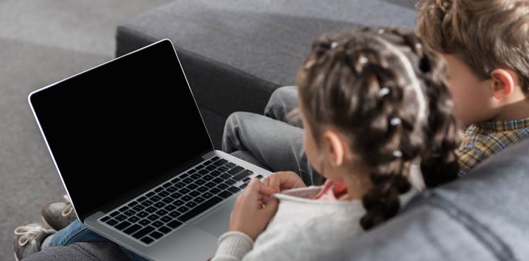 To børn sidder og ser på en bærbar computer